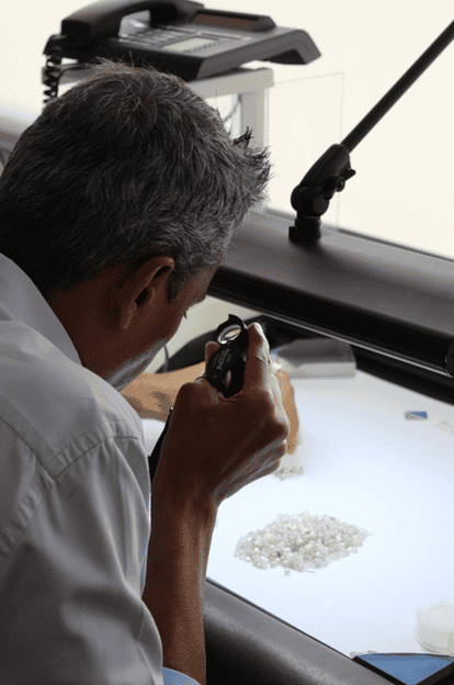 An Indian diamantaire inspecting rough diamonds during a tender at Bonas-Couzyn.